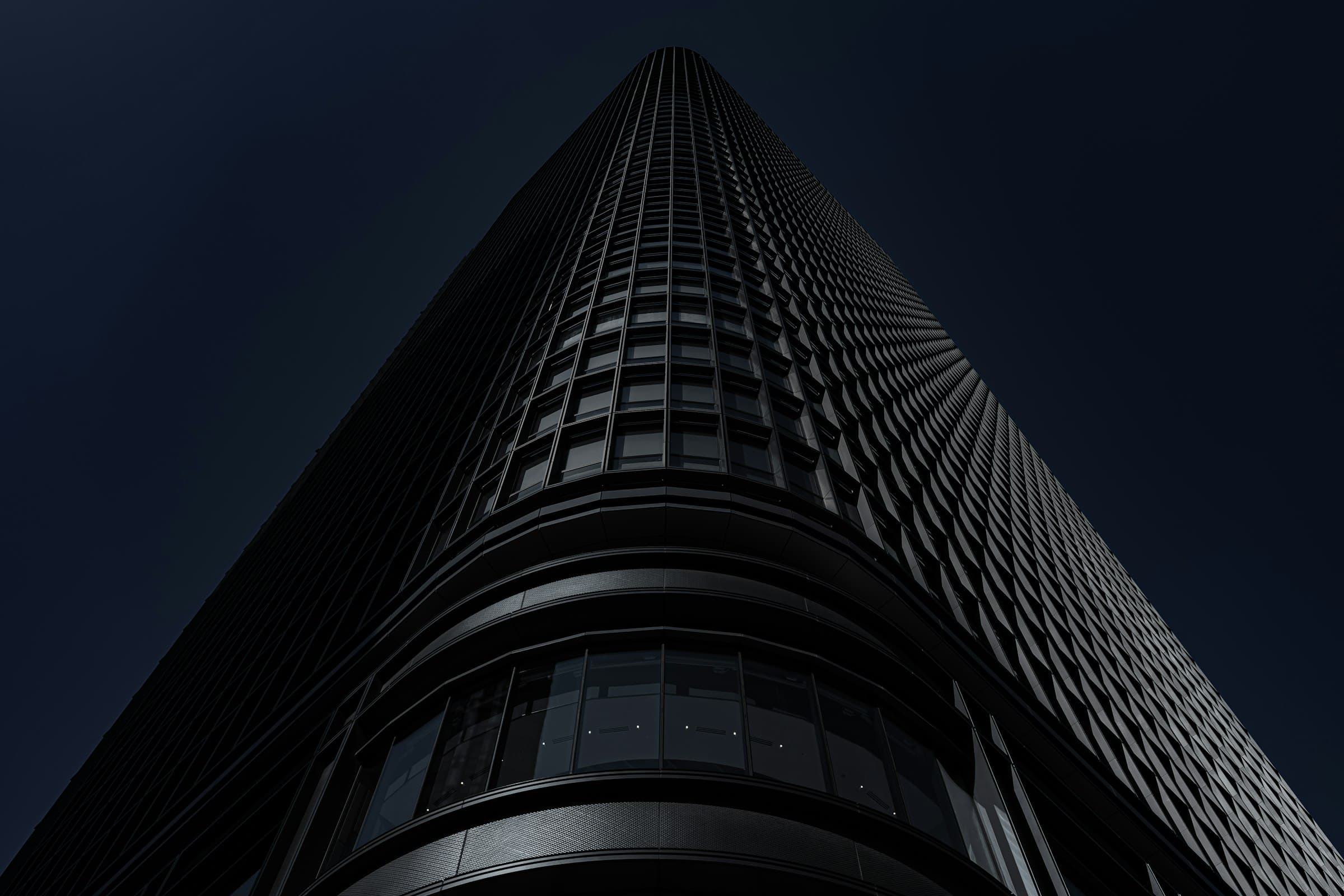 Looking up a dark glass tower against a night sky