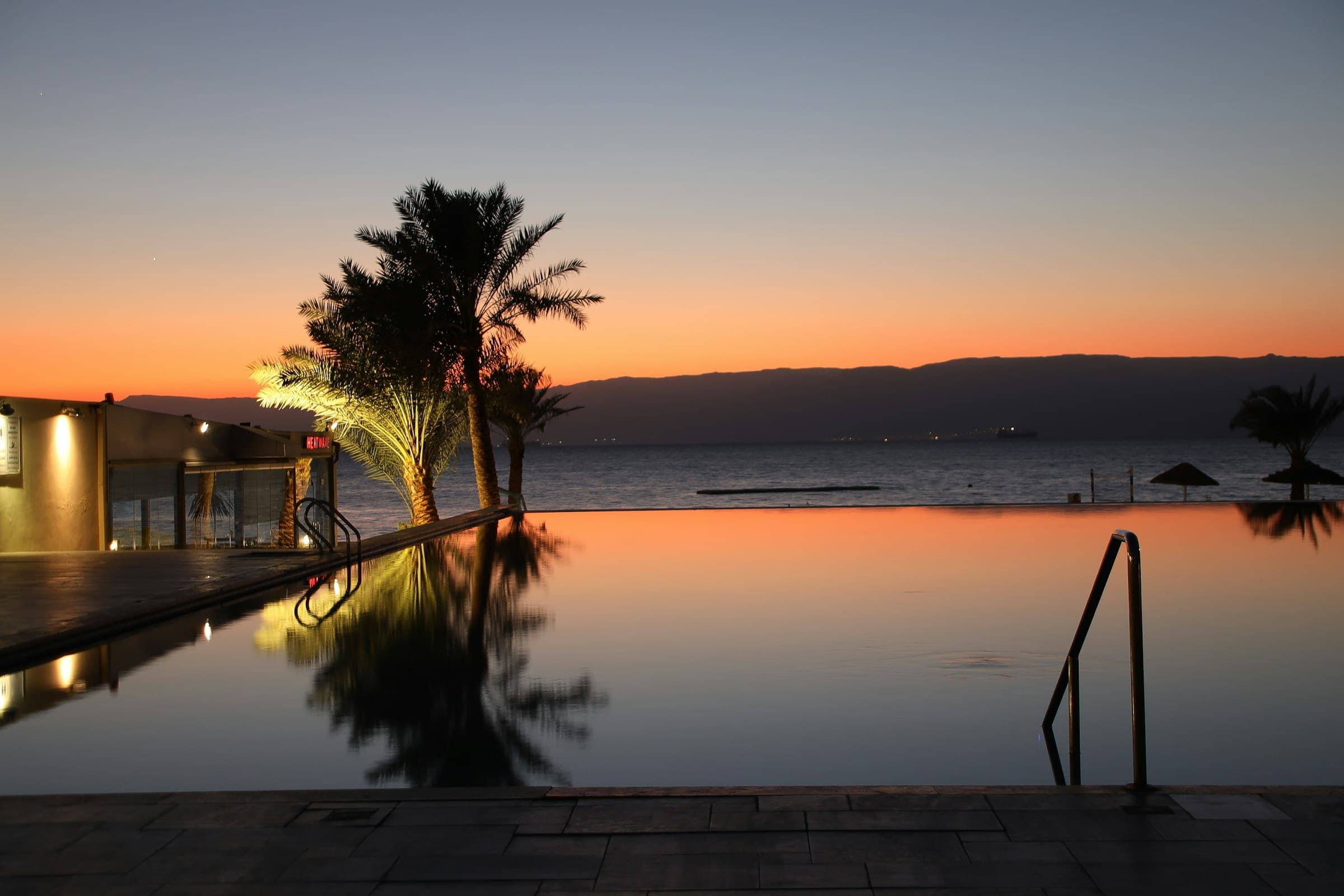 Infinity pool reflecting palms at sunset