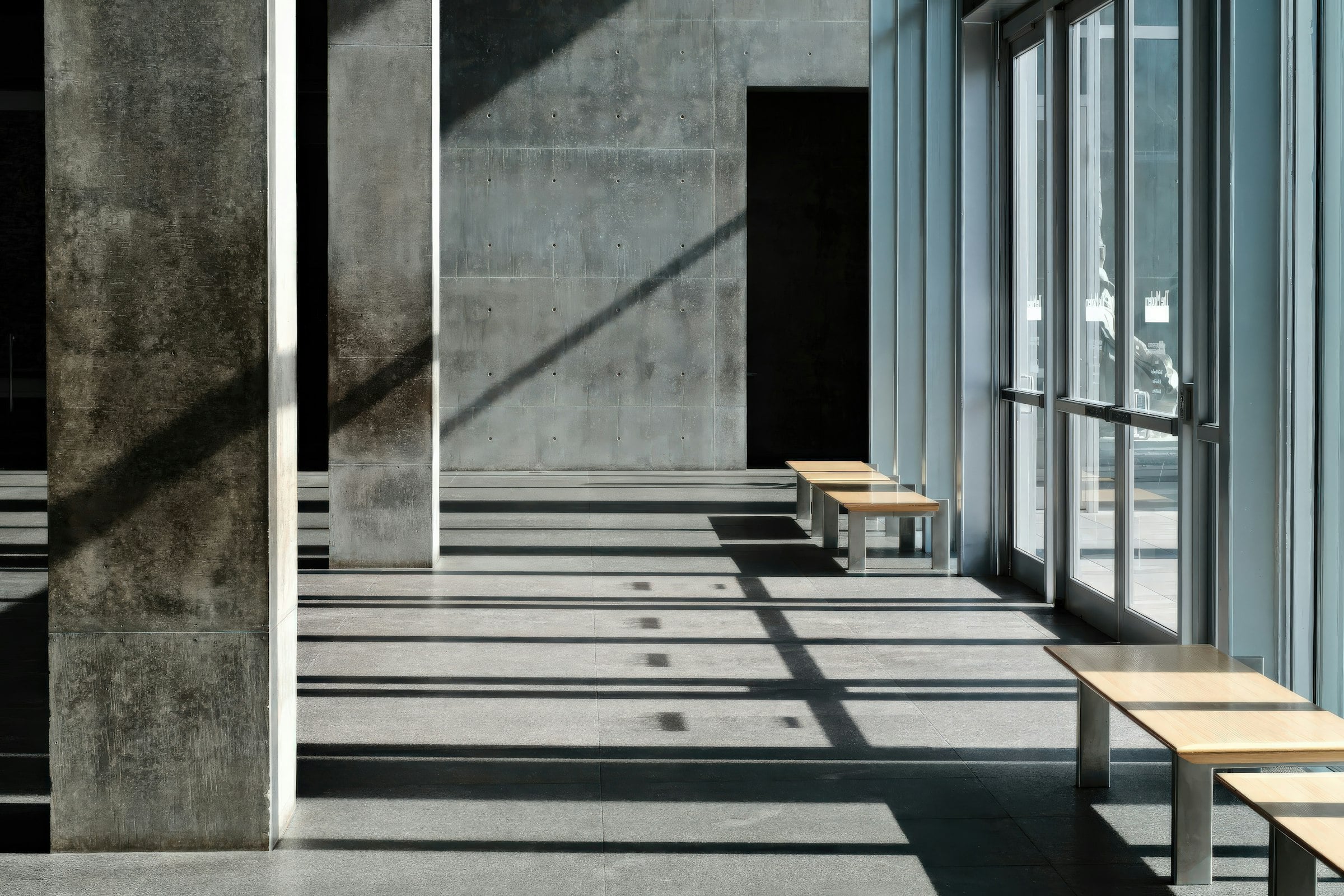 Concrete colonnade with bands of sunlight across the floor